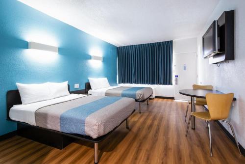 a hotel room with two beds and a table at Motel 6-Jacksonville, NC in Jacksonville