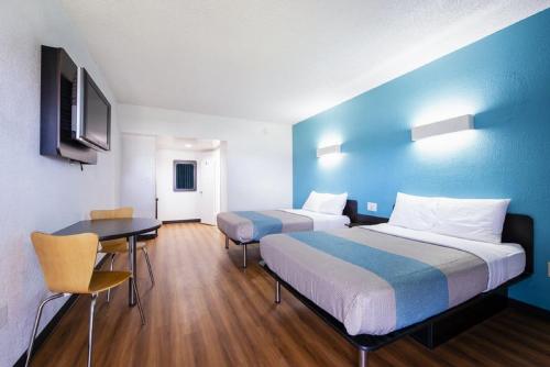 a hotel room with two beds and a table and a desk at Motel 6-Jacksonville, NC in Jacksonville