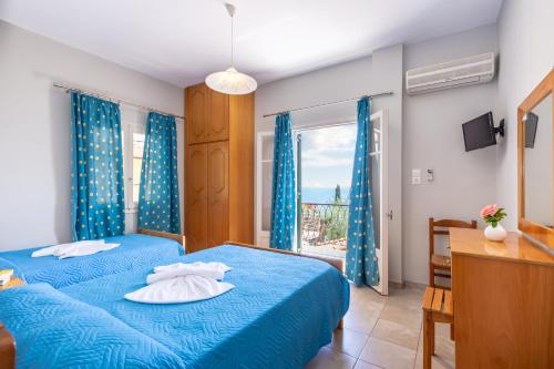 a bedroom with a blue bed and a window at Rapanos Apartments in Paleokastritsa
