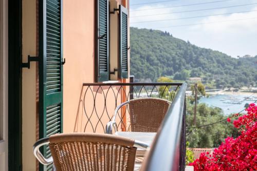 a balcony with chairs and a table and flowers at Rapanos Apartments in Paleokastritsa