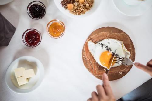 a table with a plate of food with a egg on it at Hotel Berghang in Collepietra