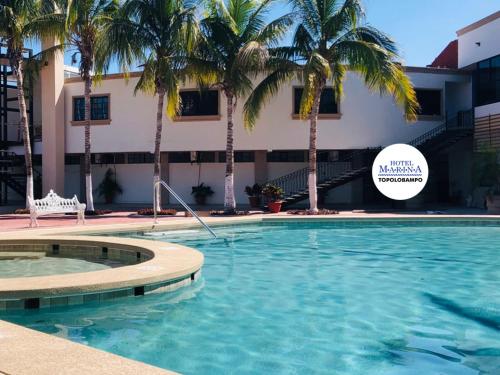 a swimming pool with palm trees in front of a building at Hotel Marina Topolobampo in Topolobampo