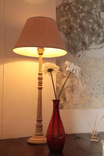 a lamp sitting on a table next to a vase with flowers at Casa Colonial Koenig in São Filipe