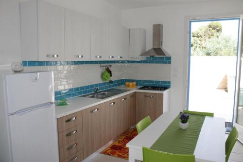 マリーナ・ディ・マンカヴェルサにあるLondazzurraのキッチン(白い冷蔵庫、テーブル、緑の椅子付)