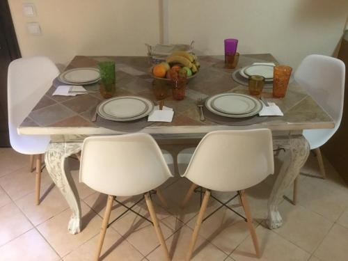a table with chairs and plates and fruit on it at SUNNY STUDIO in Skala Marion