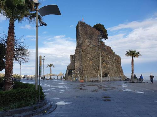 eine große Steinmauer mit Palmen auf einer Straße in der Unterkunft Charme in Aci Castello in Aci Castello