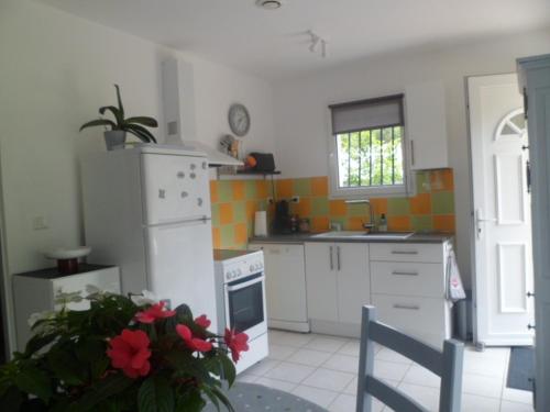 Il comprend une cuisine équipée d'un réfrigérateur blanc et d'une cuisinière. dans l'établissement maisonnette entre forêt et occéan, à Vendays-Montalivet