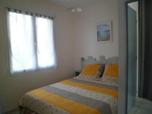 ein Schlafzimmer mit einem Bett und zwei Fenstern in der Unterkunft maisonnette entre forêt et occéan in Vendays-Montalivet