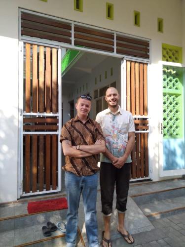 two men are standing in front of a building at LG Homestay in Kepanjen