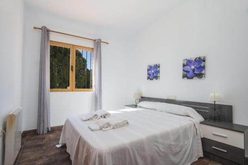 a white bedroom with a bed with slippers on it at Villa Fanadix - Plusholidays in Benissa