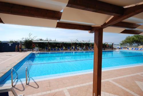 a swimming pool at a resort with people sitting around it at Camping Village La Pineta in San Vito lo Capo