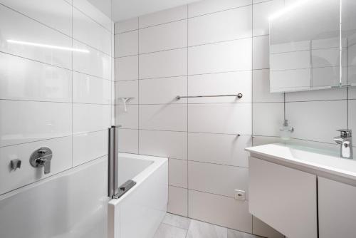 uma casa de banho branca com uma banheira e um lavatório em LAAX Homes - Runca 752 em Flims