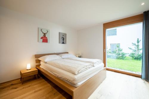 a bedroom with a bed and a large window at Casa Miraselva in Flims