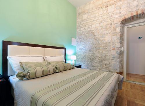 um quarto com uma cama grande e uma parede de pedra em Palace Augubio em Split