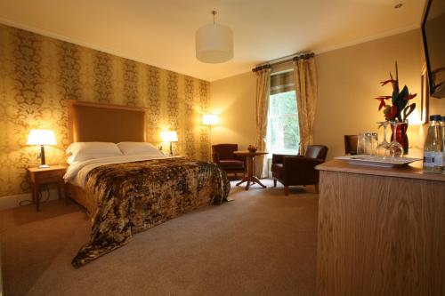 Habitación de hotel con cama, mesa y sillas en Farington Lodge Hotel, en Preston
