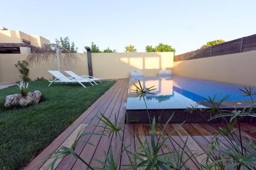 a backyard with a swimming pool and two lawn chairs at Lida Garden Loft in Anavissos