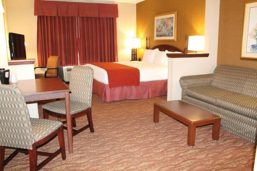 a hotel room with a bed and a couch and a table at Auburn Place Hotel & Suites Paducah in Paducah