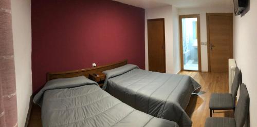 1 dormitorio con 2 camas y pared roja en Hostal El Arco, en Almazán