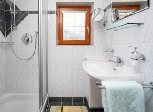a white bathroom with a sink and a shower at Haus Dabaklamm in Kals am Großglockner
