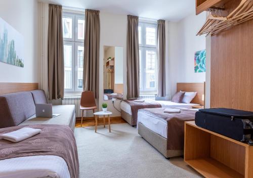 una camera d'albergo con due letti e un divano di Booking En Suite a Belgrado