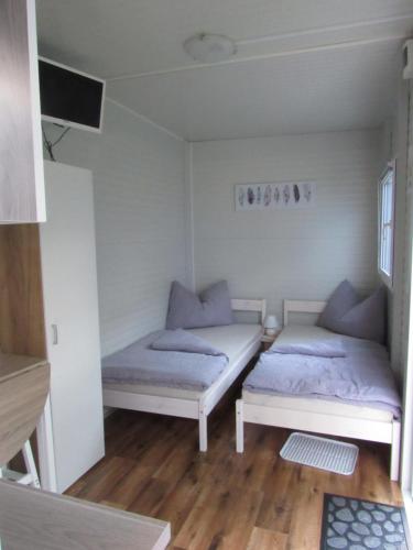 2 Betten in einem kleinen Zimmer mit Holzböden in der Unterkunft Ferienwohnungen Köckhausen Nähe Red Bull Ring in Rattenberg