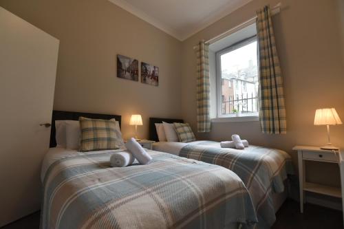 2 camas individuales en una habitación con ventana en Pleasance Apartment Ground Floor Main Door Access, en Edimburgo