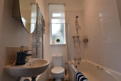 a bathroom with a sink and a toilet and a tub at Pleasance Apartment Ground Floor Main Door Access in Edinburgh