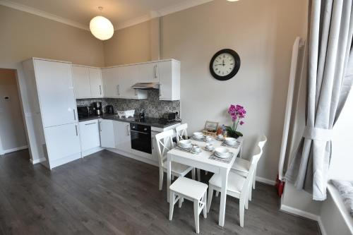 a kitchen with a table and chairs and a clock at Pleasance Apartment Ground Floor Main Door Access in Edinburgh