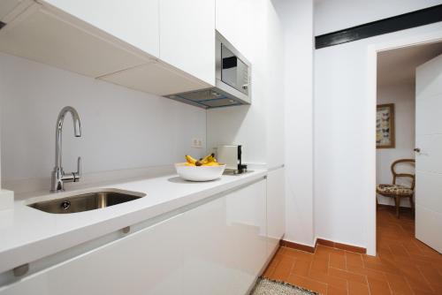 una cocina con encimeras blancas y fregadero en Casa Galera Historic Downtown Apartment in Seville en Sevilla