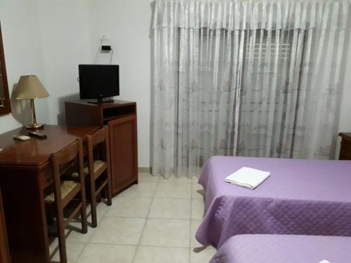 a bedroom with a bed and a desk and a tv at Castelvetere Hotel in Caulonia