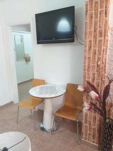 a table and chairs with a tv on a wall at Guest House Orlihome in Haifa