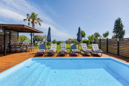 una piscina con sedie e una terrazza con tavolo di Nastazia Luxury Beach House a Ialyssos