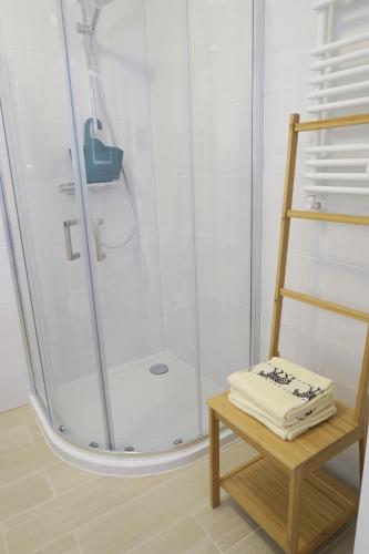 een badkamer met een douche en een houten kruk bij Biały apartament in Kołobrzeg