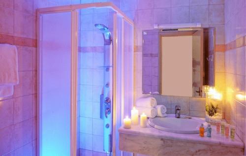 uma casa de banho com um lavatório e um chuveiro com um espelho. em Aegean Sky Hotel-Suites em Malia