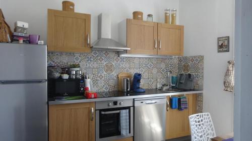 a kitchen with wooden cabinets and a refrigerator at Le Compostelle Chic, Charme, Confort, Cocooning 80 m² in Saint-Léonard-de-Noblat