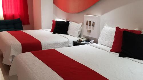 Dos camas en una habitación de hotel con rojo y blanco en Hotel Dluxe, en San Juan de los Lagos