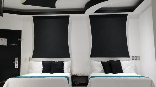 two beds in a room with black and white at Hotel Dluxe in San Juan de los Lagos
