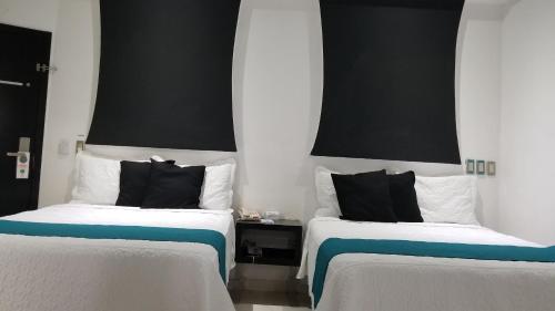 two beds sitting next to each other in a room at Hotel Dluxe in San Juan de los Lagos