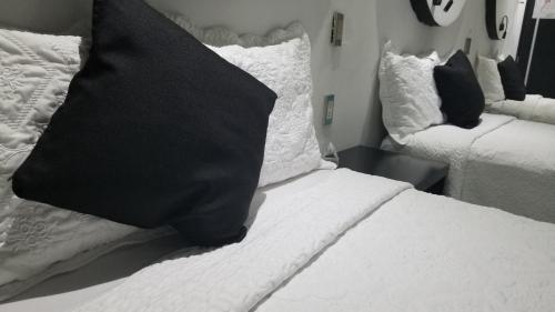 a black pillow sitting on a bed with white pillows at Hotel Dluxe in San Juan de los Lagos