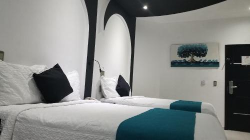 a bedroom with two beds with white and blue at Hotel Dluxe in San Juan de los Lagos