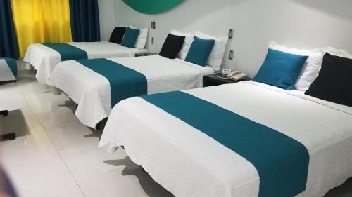 three beds in a hotel room with blue and white sheets at Hotel Dluxe in San Juan de los Lagos
