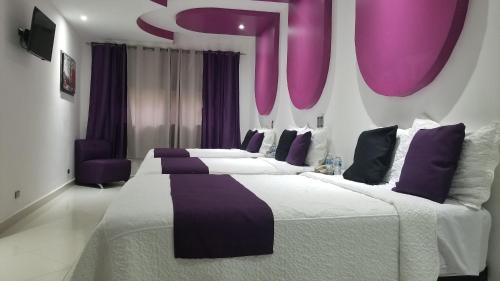 a bedroom with two large beds with purple accents at Hotel Dluxe in San Juan de los Lagos