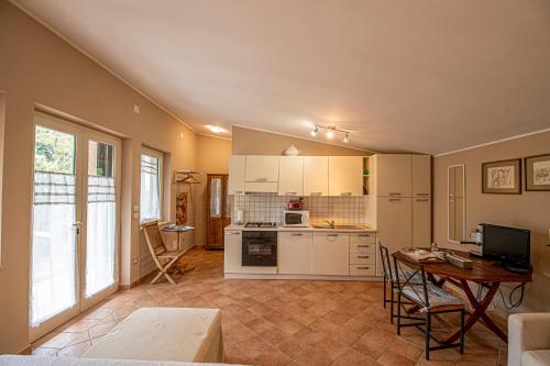una cocina con armarios blancos y una mesa en una habitación en Un Giardino sul Lago, en Montefiascone