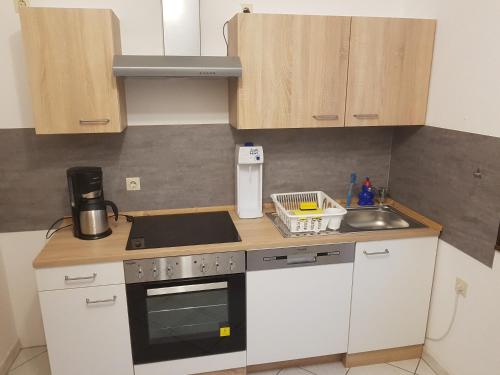 a kitchen with white cabinets and a stove and a sink at Ferienwohnung Hampel in Eisenach