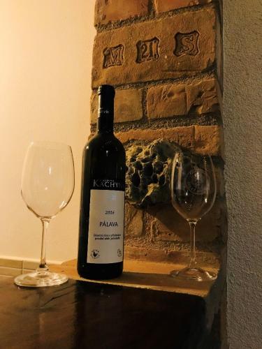 a bottle of wine and two glasses on a table at Sklípek u Svobodů in Velké Bílovice