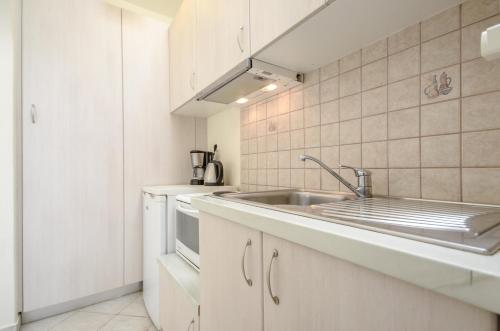 a kitchen with white cabinets and a sink at Orkos Blue Coast in Mikri Vigla