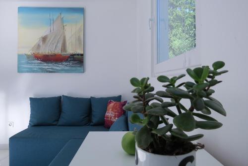 a living room with a blue couch and a plant at BUNGALOW VICE with pool in Pakoštane