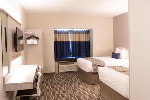 a hotel room with two beds and a window at Microtel Inn & Suites by Wyndham Springville in Springville