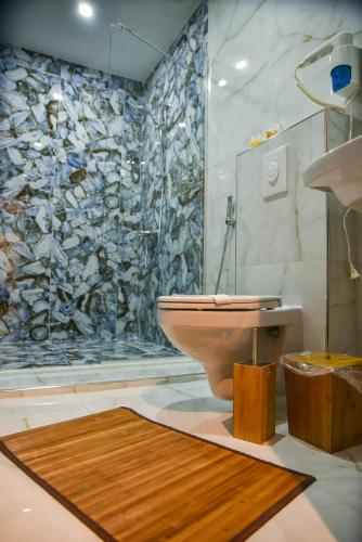 a bathroom with a toilet and a stone wall at Padam Hotel & SPA in Ulcinj