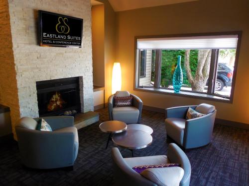 a living room with couches chairs and a fireplace at Eastland Suites Hotel & Conference Ctr, Trademark by Wyndham in Bloomington